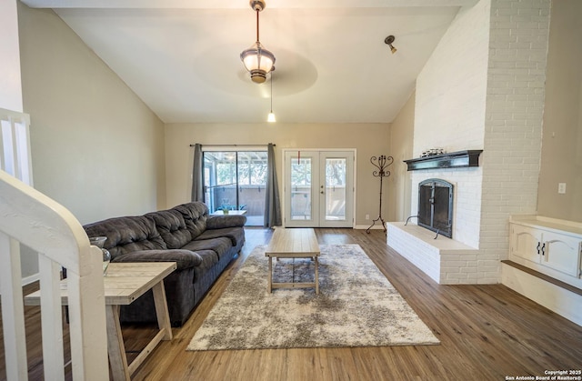 living room featuring ceiling fan, a fireplace, french doors, wood finished floors, and high vaulted ceiling