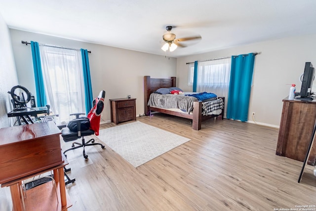 bedroom featuring baseboards, wood finished floors, and a ceiling fan