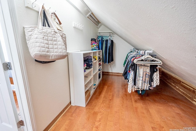 walk in closet featuring vaulted ceiling and light wood-style flooring