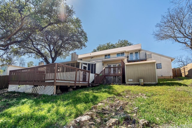 rear view of house featuring a lawn, a deck, and fence