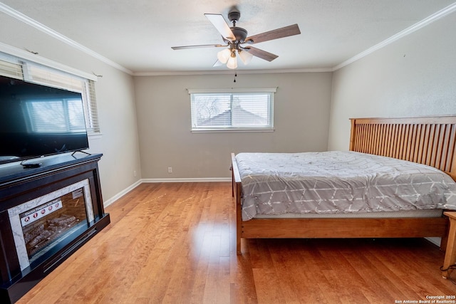 bedroom featuring ceiling fan, crown molding, baseboards, and wood finished floors