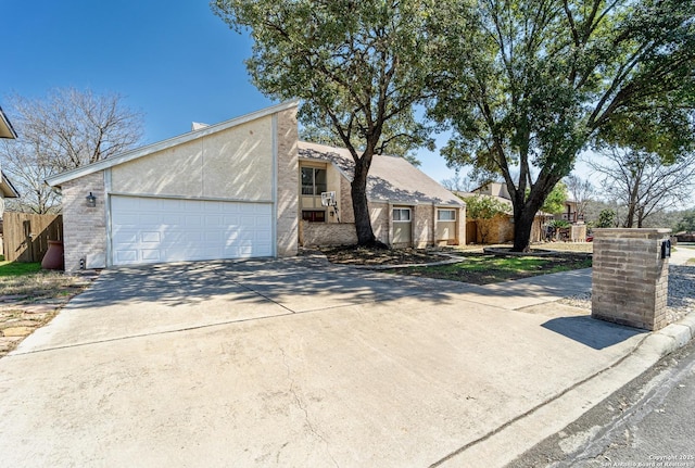 mid-century modern home with concrete driveway, an attached garage, and fence