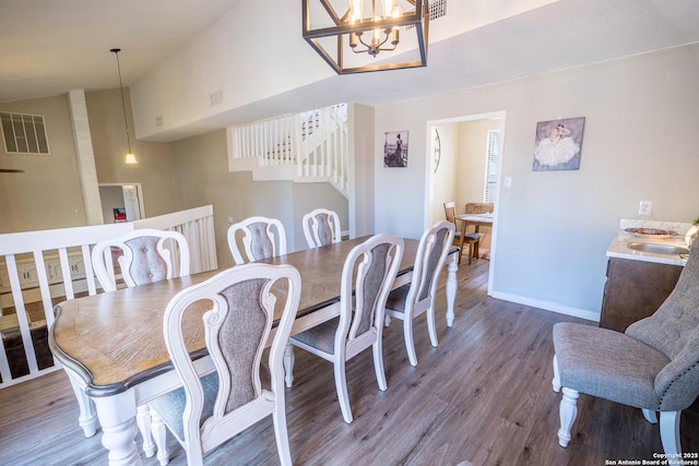 dining space with visible vents, wood finished floors, baseboards, lofted ceiling, and a chandelier