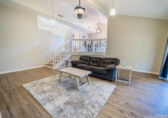 living room with vaulted ceiling, wood finished floors, baseboards, and visible vents