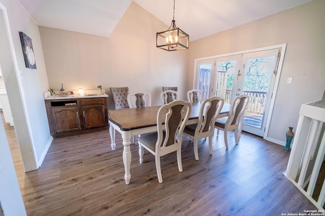 dining space featuring dark wood-style floors, a notable chandelier, baseboards, and vaulted ceiling