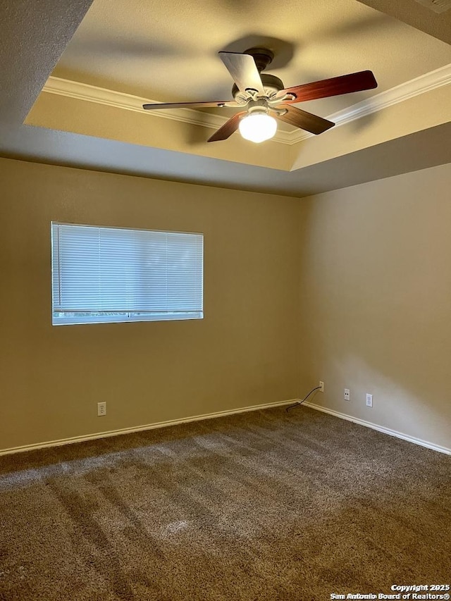 spare room featuring a tray ceiling, dark carpet, and ornamental molding