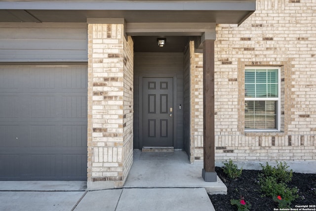 entrance to property with a garage and brick siding