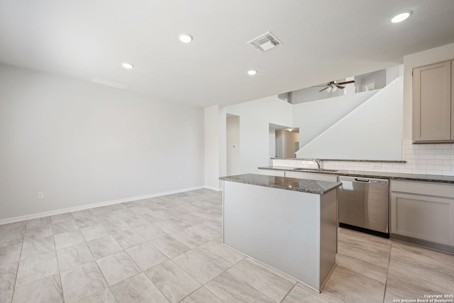 kitchen with visible vents, a sink, dark stone countertops, a kitchen island, and dishwasher