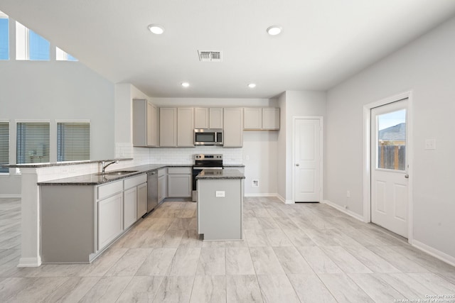 kitchen with visible vents, gray cabinetry, stainless steel appliances, and dark stone counters