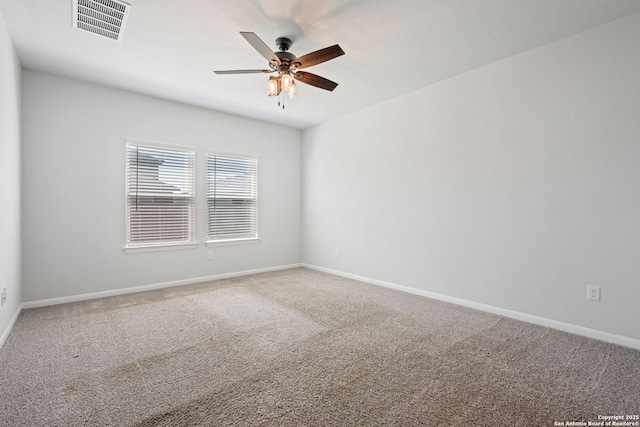 carpeted empty room featuring a ceiling fan, visible vents, and baseboards