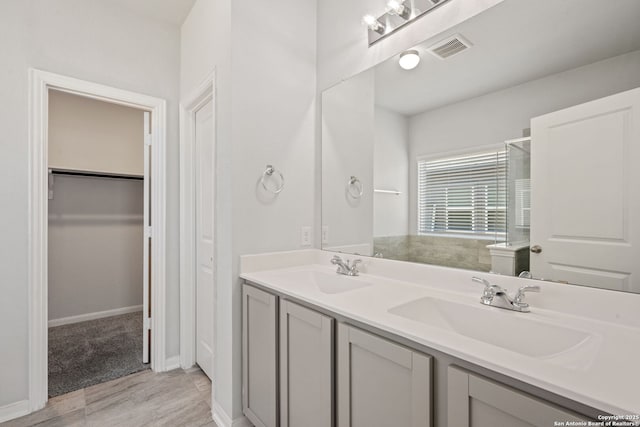 full bathroom with double vanity, visible vents, a shower stall, and a sink