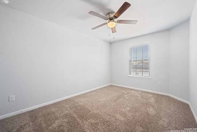 carpeted spare room with a ceiling fan and baseboards