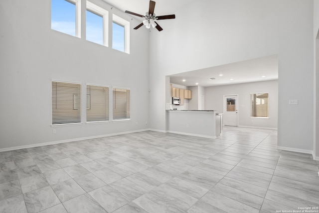 unfurnished living room featuring recessed lighting, plenty of natural light, a ceiling fan, and baseboards