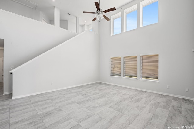 unfurnished living room with baseboards, ceiling fan, and a towering ceiling