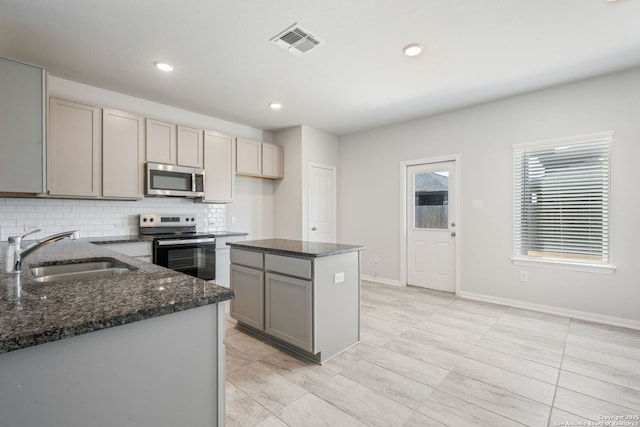 kitchen with stainless steel microwave, visible vents, gray cabinets, electric stove, and a sink