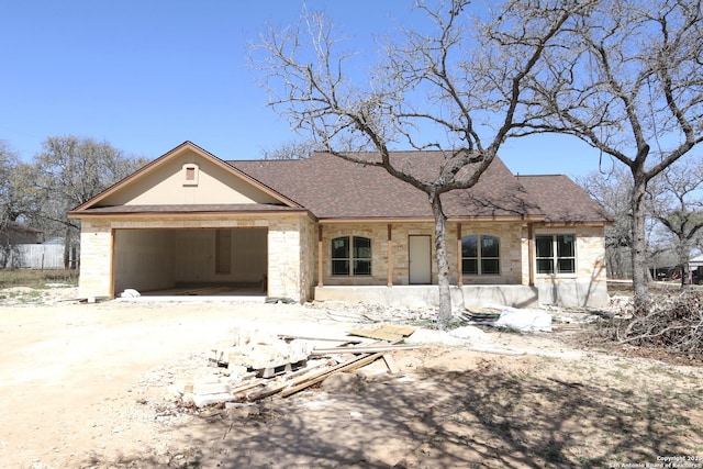 view of front of home with a garage, stone siding, roof with shingles, and driveway