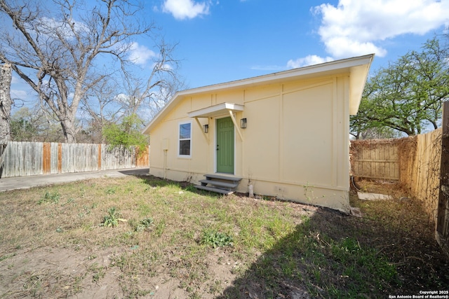 view of front of home featuring entry steps, a front yard, and a fenced backyard