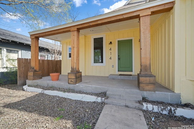 entrance to property with a porch, board and batten siding, and fence