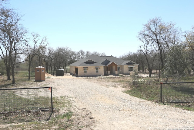 view of front of house featuring an outbuilding, driveway, a storage unit, and fence