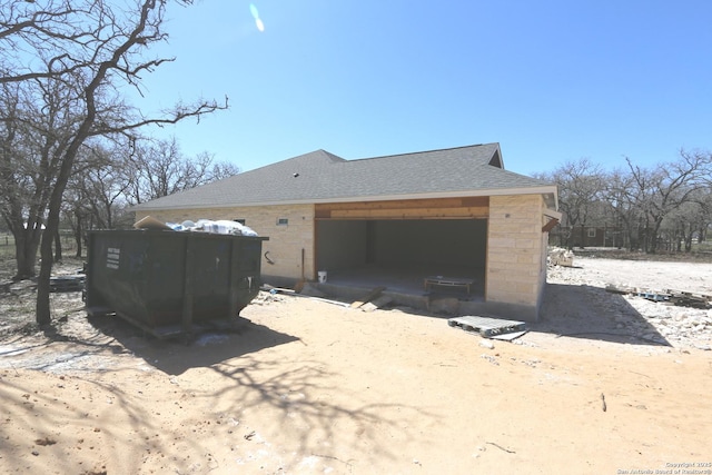 view of home's exterior featuring a garage and roof with shingles