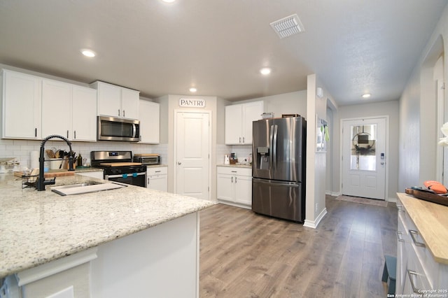 kitchen featuring light wood-type flooring, visible vents, a sink, white cabinetry, and stainless steel appliances