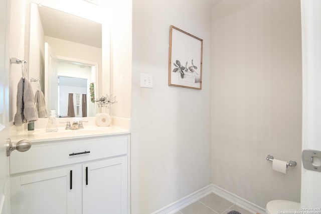 bathroom with baseboards, toilet, vanity, and tile patterned flooring