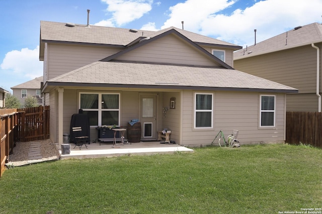 back of house with a patio, a lawn, a fenced backyard, and roof with shingles