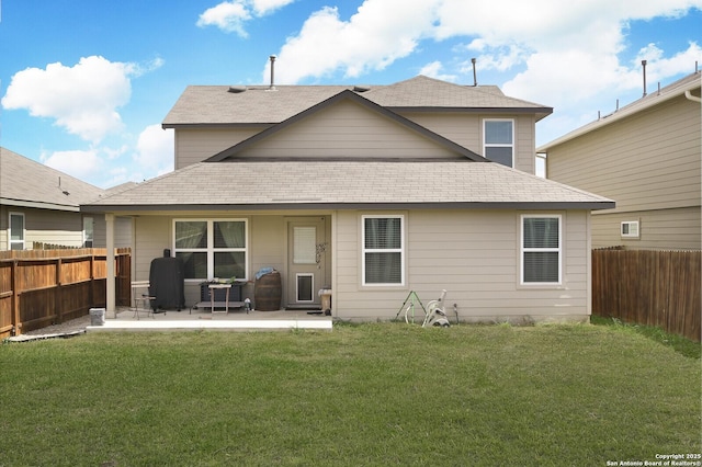 rear view of property featuring a lawn, a fenced backyard, and a shingled roof