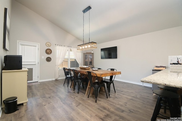 dining space featuring lofted ceiling, baseboards, and dark wood-style flooring