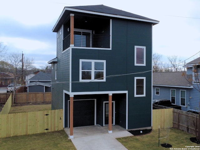 view of front of property featuring a front lawn, concrete driveway, fence, and a garage