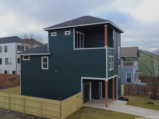 back of property featuring a patio area, a balcony, a lawn, and fence