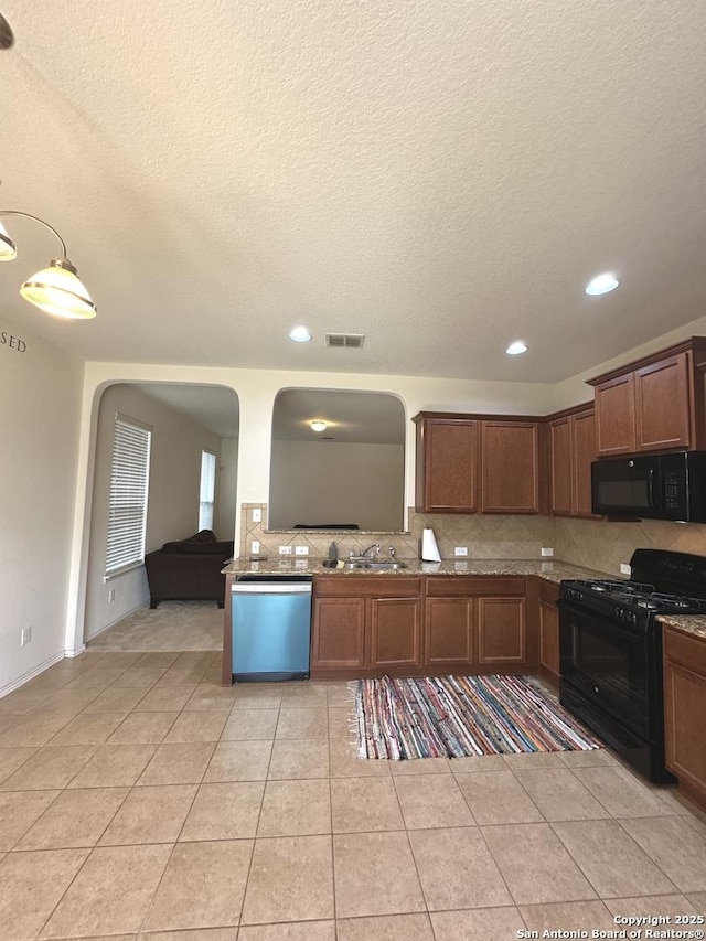 kitchen with visible vents, decorative backsplash, arched walkways, black appliances, and a sink