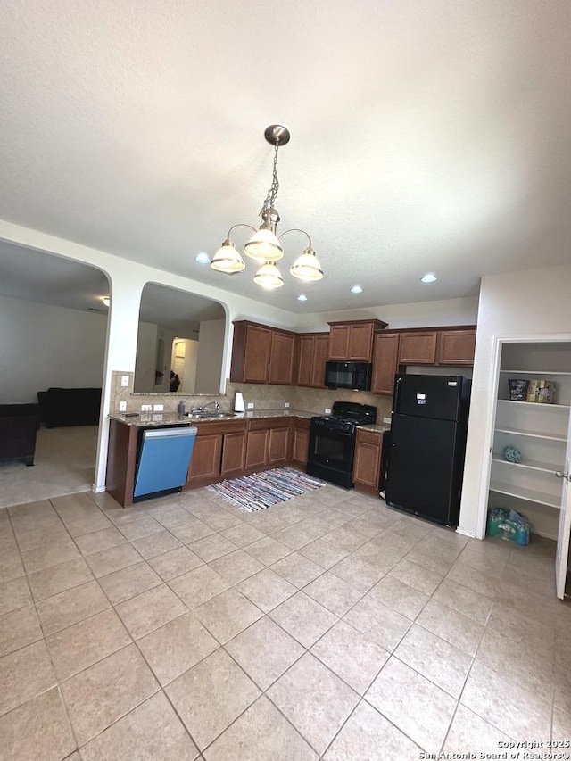 kitchen featuring decorative backsplash, black appliances, a notable chandelier, and arched walkways