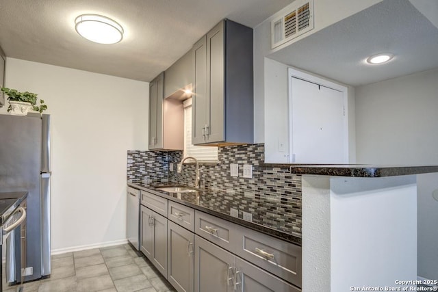 kitchen featuring visible vents, gray cabinetry, a sink, tasteful backsplash, and stainless steel appliances