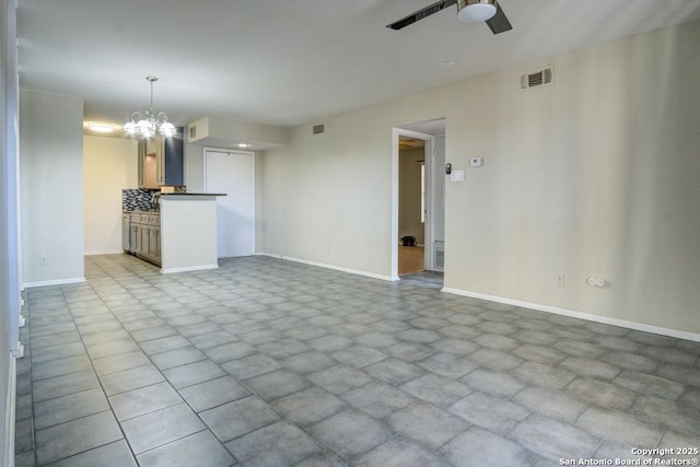 unfurnished living room featuring visible vents, baseboards, and ceiling fan with notable chandelier