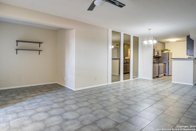 unfurnished living room with ceiling fan with notable chandelier and baseboards