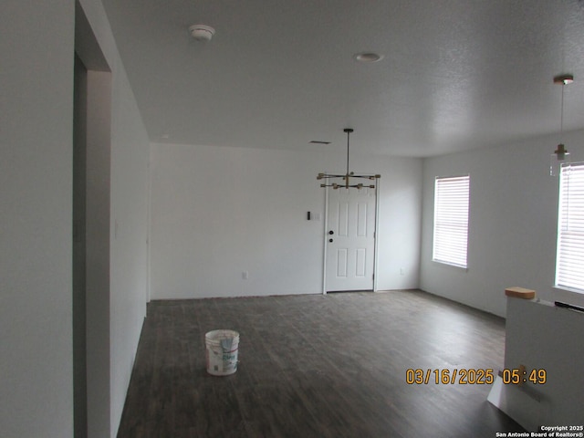 empty room featuring an inviting chandelier and wood finished floors