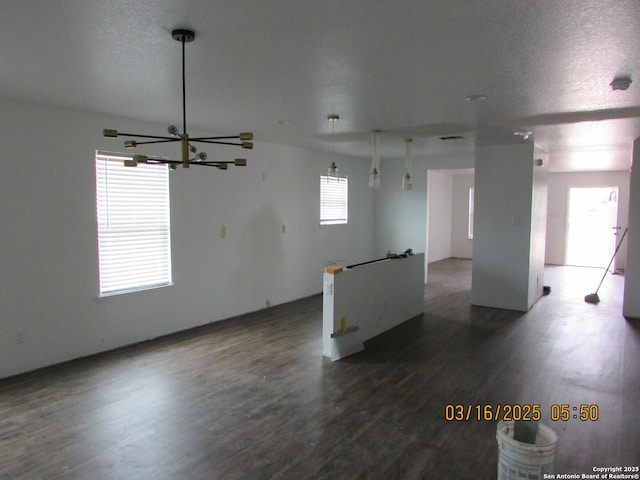 unfurnished room featuring dark wood-type flooring, a chandelier, and a textured ceiling