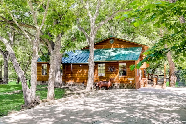 view of front of property with log veneer siding, metal roof, and a front yard