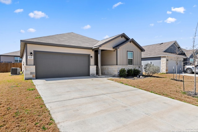 view of front of property featuring driveway, stone siding, board and batten siding, a front yard, and a garage