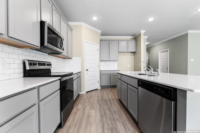 kitchen with gray cabinetry, stainless steel appliances, light wood-type flooring, and a sink