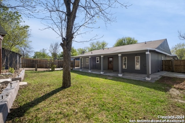 rear view of house featuring a fenced backyard, a lawn, and a patio