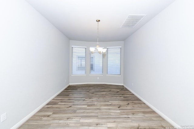 interior space with an inviting chandelier, light wood-style flooring, baseboards, and visible vents