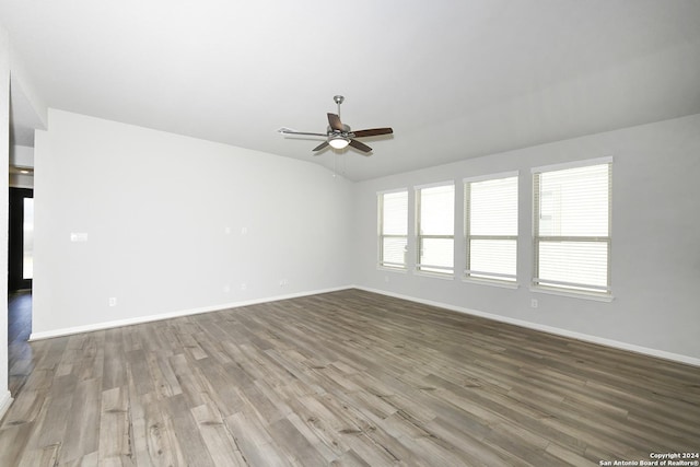 empty room featuring wood finished floors, baseboards, and ceiling fan