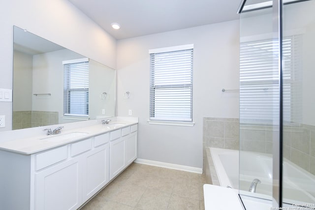 full bathroom with tiled bath, a wealth of natural light, and a sink