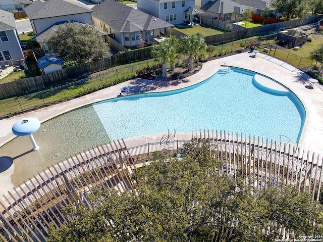 community pool with a patio, fence, and a residential view