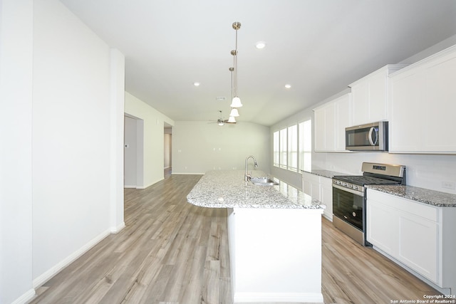 kitchen with a center island with sink, stainless steel appliances, light wood-style floors, and a sink