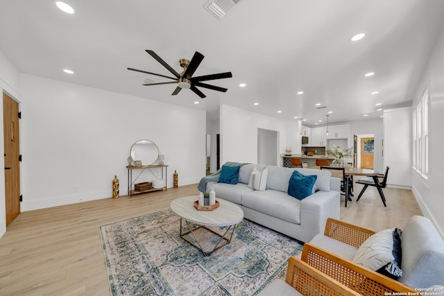 living room featuring visible vents, baseboards, recessed lighting, light wood-style floors, and a ceiling fan