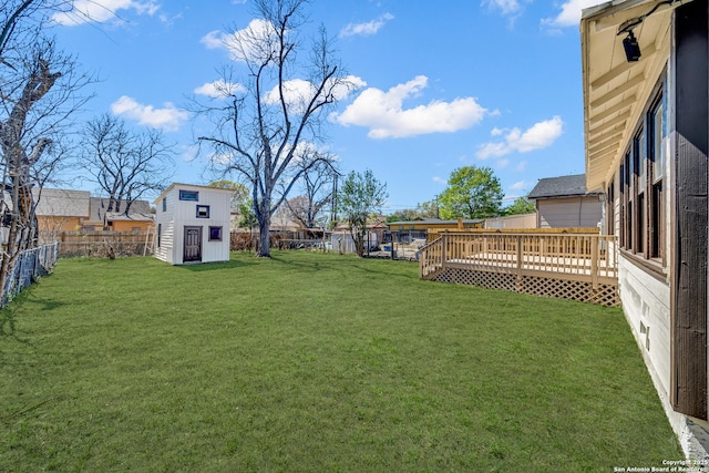 view of yard featuring a shed, a wooden deck, a fenced backyard, and an outdoor structure