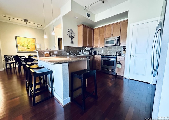 kitchen with tasteful backsplash, a breakfast bar area, appliances with stainless steel finishes, hanging light fixtures, and dark wood-style flooring